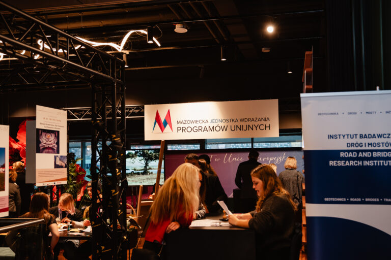 Stoisko Mazowieckiej Jednostki Wdrażania Programów Unijnych podczas 14. Forum Rozwoju Mazowsza. Uczestnicy wydarzenia zapoznają się z ofertą instytucji oraz projektami współfinansowanymi ze środków Unii Europejskiej.