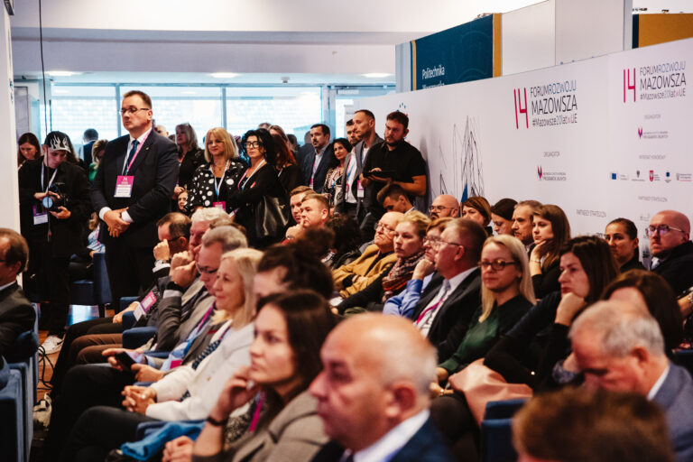 Publiczność uczestnicząca w jednej z debat podczas 14. Forum Rozwoju Mazowsza. Uczestnicy siedzą i stoją w sali konferencyjnej, uważnie słuchając prelegentów. W tle widoczna ścianka z logo wydarzenia oraz Politechniki Warszawskiej.