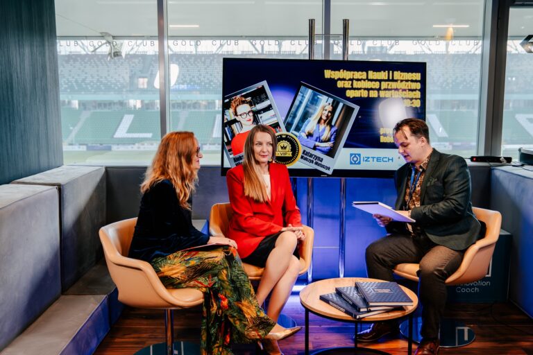 Wywiad w strefie medialnej Forum Rozwoju Mazowsza. Na ekranie widoczny temat rozmowy o współpracy nauki i biznesu oraz kobiecym przywództwie. W tle stadion, a uczestnicy siedzą w studyjnej aranżacji z logotypem IZTECH i Innovation Coach.