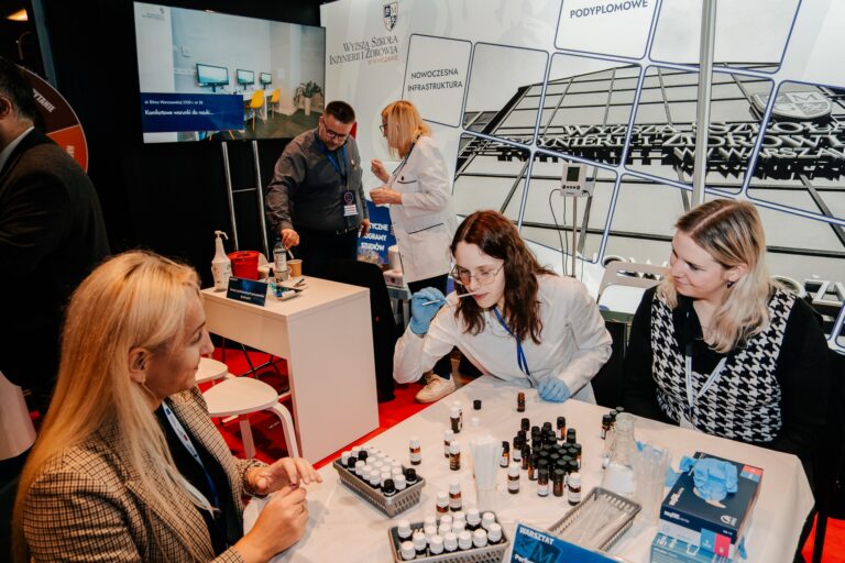 Stoisko Wyższej Szkoły Inżynierii i Zdrowia w Warszawie podczas 15. Forum Rozwoju Mazowsza, na którym uczestnicy biorą udział w warsztatach laboratoryjnych z zakresu chemii i kosmetologii.