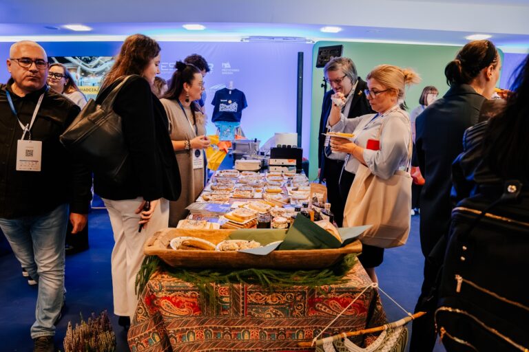 Uczestnicy 15. Forum Rozwoju Mazowsza degustują regionalne potrawy przy stoisku promującym Województwo Podkarpackie. Na stole rozłożone są tradycyjne przysmaki i produkty lokalne