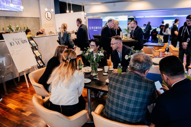 Uczestnicy 15. Forum Rozwoju Mazowsza rozmawiają przy stolikach w strefie networkingowej. W tle widoczne są stoiska Unimos Alliance i Maxfliz oraz tablica z napisem „Celebrating 10 Years