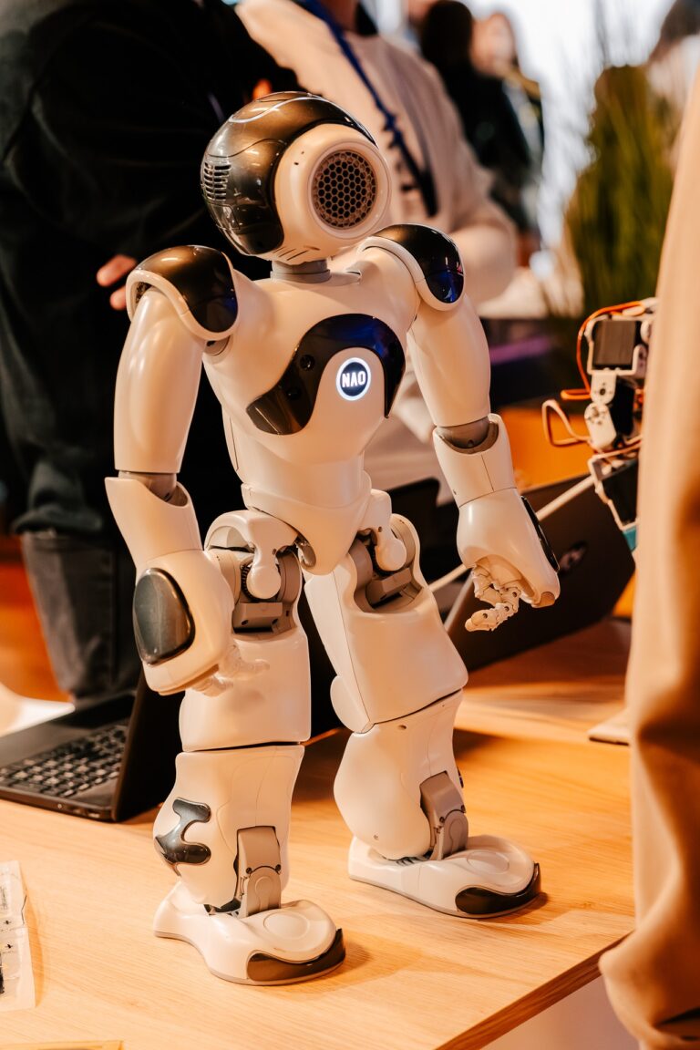 Robot humanoidalny NAO stojący na stole demonstracyjnym podczas 15. Forum Rozwoju Mazowsza, prezentowany jako przykład nowoczesnych technologii.
