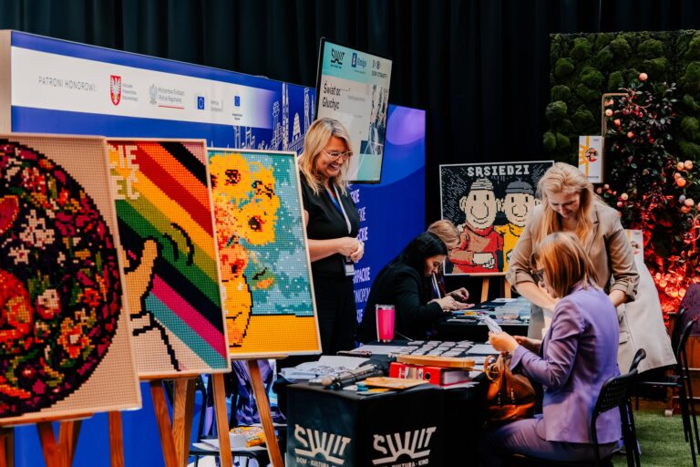 Stoisko Domu Kultury Świt podczas 15. Forum Rozwoju Mazowsza. Na sztalugach stoją kolorowe mozaiki z koralików, a uczestnicy wykonują własne prace artystyczne przy stole warsztatowym.