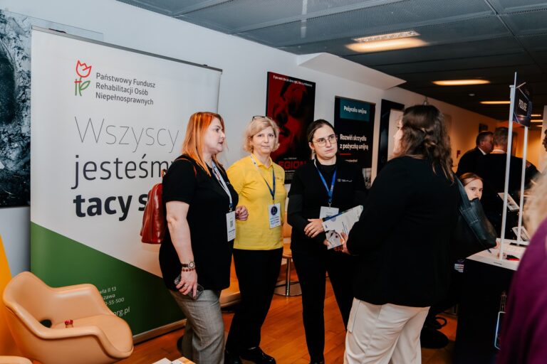 Strefa Państwowego Funduszu Rehabilitacji Osób Niepełnosprawnych (PFRON) podczas 15. Forum Rozwoju Mazowsza – przedstawicielki funduszu rozmawiają z uczestniczkami wydarzenia przy stoisku promującym hasło „Wszyscy jesteśmy tacy sami”.