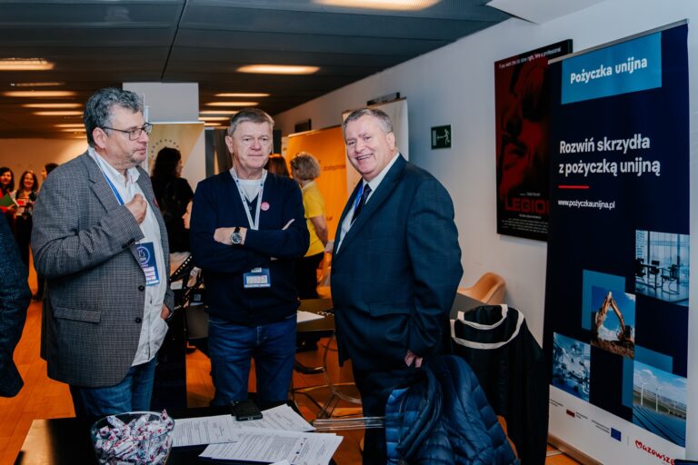 Trzej mężczyźni rozmawiają w strefie networkingowej podczas 15. Forum Rozwoju Mazowsza.