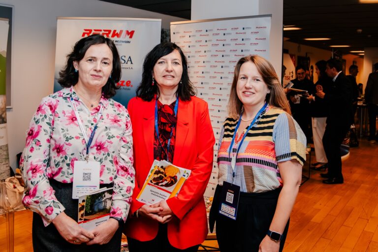 Trzy kobiety uczestniczące w 15. Forum Rozwoju Mazowsza pozują do wspólnego zdjęcia w strefie wystawienniczej wydarzenia.
