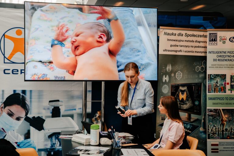 Stoisko CEPT – Centrum Edukacji i Promocji Transferu podczas 15. Forum Rozwoju Mazowsza. Dwie kobiety rozmawiają przy stanowisku, na ekranie widać zdjęcie noworodka, a w tle banery z informacjami o badaniach naukowych i diagnostyce medycznej.